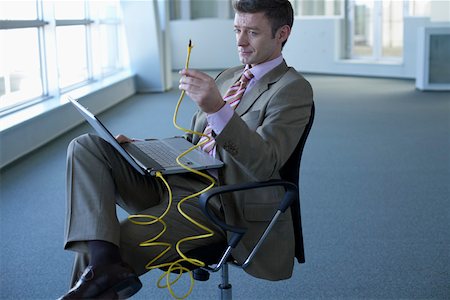 simsearch:628-01639078,k - Businessman with laptop on lap holding an network cable Foto de stock - Sin royalties Premium, Código: 628-01639044