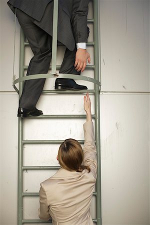 Businessman on fire escape, reaching down to businesswoman's hand below Stock Photo - Premium Royalty-Free, Code: 628-01712293