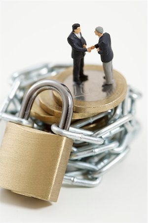 simsearch:628-01712179,k - Businessmen figurines shaking hands on a stack of coins wrapped of a chain with a padlock Stock Photo - Premium Royalty-Free, Code: 628-01712330