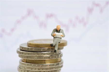 simsearch:628-01712179,k - Businessman figurine sitting on stack of coins while reading Stock Photo - Premium Royalty-Free, Code: 628-01712350