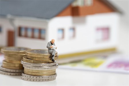 simsearch:628-01712237,k - Businessman figurine sitting on stack of coins while reading, miniature house in background Foto de stock - Royalty Free Premium, Número: 628-01712364