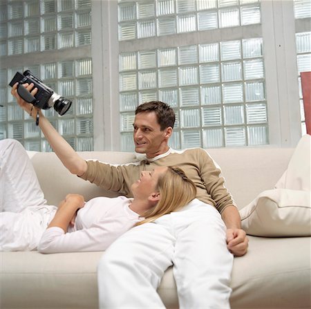 Man filming a blond woman on the settee - Couple - Hobby - Living Room Stock Photo - Premium Royalty-Free, Code: 628-01712380