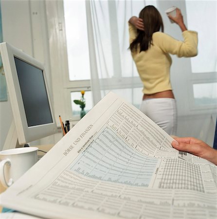 Young woman standing in front of a window while a man is reading newspaper Stock Photo - Premium Royalty-Free, Code: 628-01712408