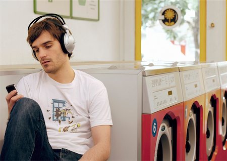 Young man in a laundromat listening to music about headphones Fotografie stock - Premium Royalty-Free, Codice: 628-02062530