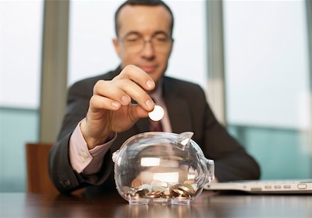 piggy bank hand - Businessman putting a coin in a piggy bank Stock Photo - Premium Royalty-Free, Code: 628-02062624