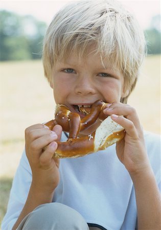 photo of people eating pretzels - Boy (6-7 years) eating pretzel Stock Photo - Premium Royalty-Free, Code: 628-02062669