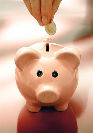 piggy bank hand - Hand putting a coin into a piggy bank Stock Photo - Premium Royalty-Free, Code: 628-02062800