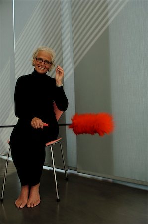 espanador de penas - Senior woman holding a feather duster sitting on chair Foto de stock - Royalty Free Premium, Número: 628-02615256