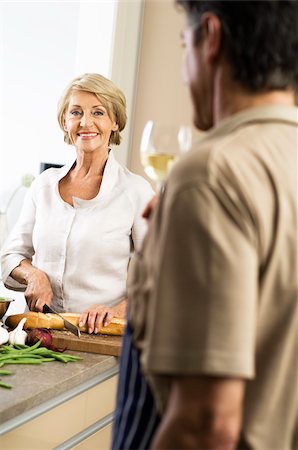 Senior woman cutting baguette, man drinking a glass of white wine Stock Photo - Premium Royalty-Free, Code: 628-02615387