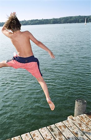 rear view boy swimsuit - Boy jumping into Water from a wooden Footbridge - Salutation - Fun - Summer - Swimming Stock Photo - Premium Royalty-Free, Code: 628-02615685