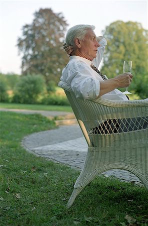 simsearch:628-02615748,k - Vieil homme dans un fauteuil de canne à sucre avec un verre de Champagne à sa main - jardin - fête - Twilight Photographie de stock - Premium Libres de Droits, Code: 628-02615745