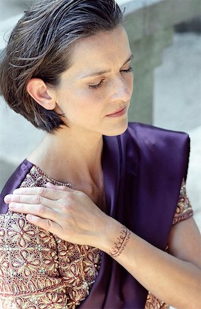 Darkhaired Woman in a Saree putting one with Henna painted Hand on her Shoulder - Meditation - Tradition Foto de stock - Sin royalties Premium, Código: 628-02954036