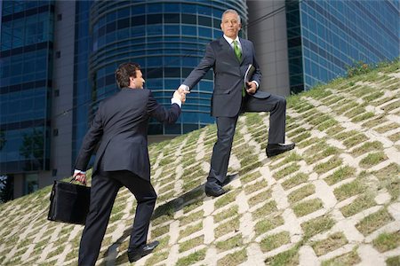 One businessman is pulling up another on a hill Stock Photo - Premium Royalty-Free, Code: 628-02954079