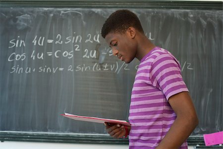 Student reading, blackboard with formula in background Stock Photo - Premium Royalty-Free, Code: 628-02954278