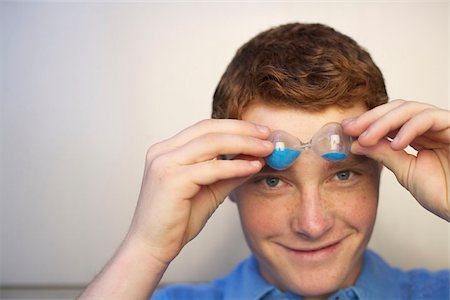 Young man holding a sand glass in front of face Stock Photo - Premium Royalty-Free, Code: 628-02954288