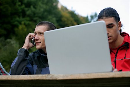 Mountaineer with mobile and laptop sitting at table Stock Photo - Premium Royalty-Free, Code: 628-02954354