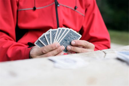 Man in a red jacket is playing cards (part of), selective focus Stock Photo - Premium Royalty-Free, Code: 628-02954366