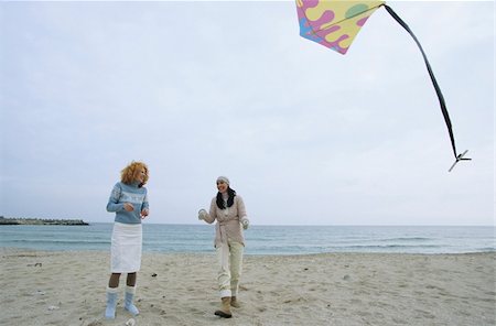 simsearch:628-02954798,k - Two female Friends laughing while a Kite flies by - Friendship - Fun - Trip - Season - Beach Fotografie stock - Premium Royalty-Free, Codice: 628-02954610