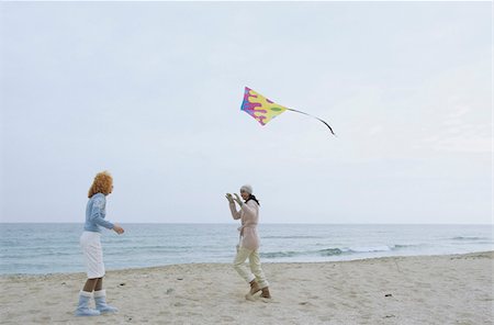 flying happy woman images - Two female Friends laughing while a Kite flies by - Friendship - Fun - Trip - Season - Beach Stock Photo - Premium Royalty-Free, Code: 628-02954638