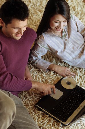 simsearch:628-02954783,k - Femme couchée à côté d'un homme avec l'ordinateur portable sur une tapis - Communication - technologie - salon Photographie de stock - Premium Libres de Droits, Code: 628-02954770