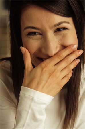 Darkhaired Woman putting one Hand over her Mouth laughing - Facial Expression - Gesture Foto de stock - Sin royalties Premium, Código: 628-02954797