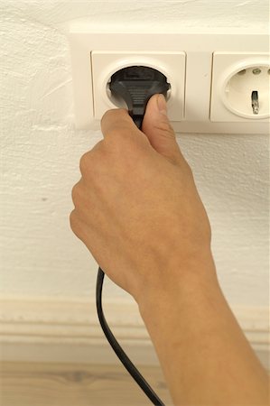 plugging in - Woman putting plug into electrical outlet Stock Photo - Premium Royalty-Free, Code: 628-02953527