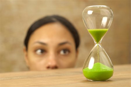 pessimism - Woman looking at hourglass with green sand Stock Photo - Premium Royalty-Free, Code: 628-02953551