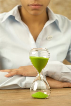 simsearch:400-04624555,k - Woman looking at hourglass with green sand Fotografie stock - Premium Royalty-Free, Codice: 628-02953572