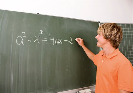Student writing formula on blackboard Stock Photo - Premium Royalty-Free, Code: 628-03058873