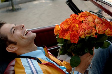 simsearch:628-03201079,k - Young man with black hair sitting in a car with a bunch of roses, close-up Stock Photo - Premium Royalty-Free, Code: 628-03201059