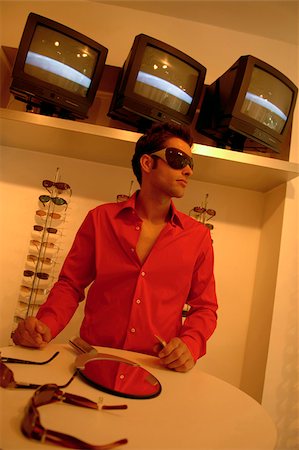 simsearch:628-03201079,k - Young man with black hair wearing big sunglasses in a shop full of eyeglasses Stock Photo - Premium Royalty-Free, Code: 628-03201061