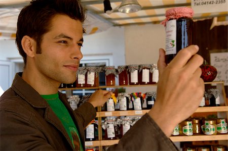 simsearch:628-03201079,k - Jeune homme aux cheveux noirs examinant un verre préserver avec de la confiture, mise au point sélective Photographie de stock - Premium Libres de Droits, Code: 628-03201113