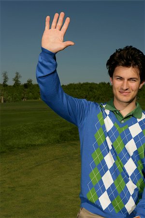 Young man on golf course raising hand Stock Photo - Premium Royalty-Free, Code: 628-03201221
