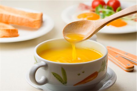 Cup Of Yellow Soup Mixed By Wooden Spoon Foto de stock - Sin royalties Premium, Código: 622-06010062
