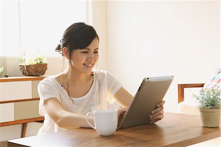 ethnic casual one not eye contact not child - Young woman using tablet in the living room Stock Photo - Premium Royalty-Free, Code: 622-06900457