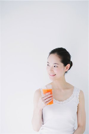 Young woman with vegetable juice smiling away Stock Photo - Premium Royalty-Free, Code: 622-06964257