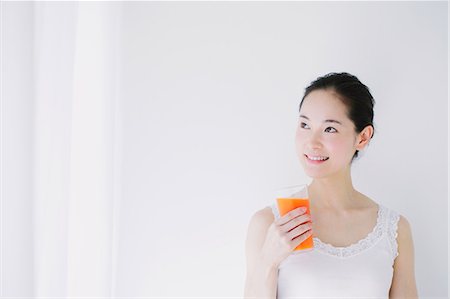 Young woman with vegetable juice smiling away Stock Photo - Premium Royalty-Free, Code: 622-06964258