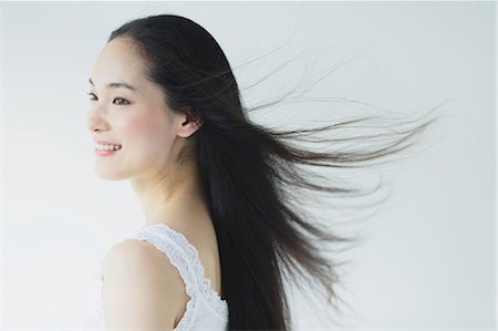 Young woman with fluttering hair smiling Stock Photo - Premium Royalty-Free, Code: 622-06964291