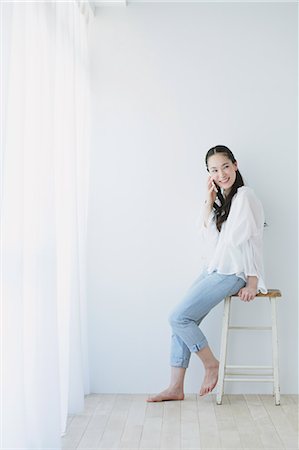 sitting room with people sitting - Young woman on the phone in the living room Stock Photo - Premium Royalty-Free, Code: 622-06964303