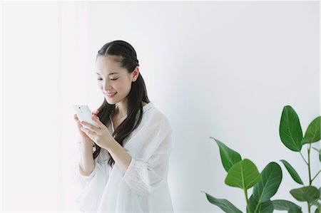 simsearch:859-06538080,k - Young woman sitting with smart phone in the living room Stock Photo - Premium Royalty-Free, Code: 622-06964318
