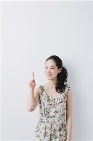 pointing (gesture) - Young woman wearing one piece pointing a finger Stock Photo - Premium Royalty-Free, Code: 622-06964336