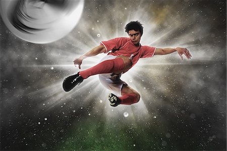 Soccer Player Kicking The Ball In Mid-Air Photographie de stock - Premium Libres de Droits, Code: 622-07736024