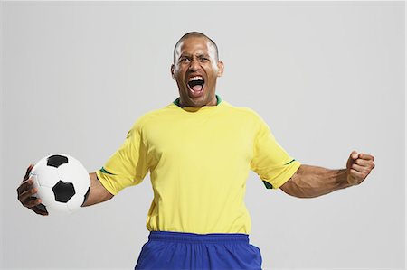 portrait of soccer player - Football player in a yellow and blue uniform standing against white background Stock Photo - Premium Royalty-Free, Code: 622-07736035
