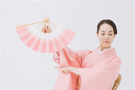 folding - Young Japanese woman in a traditional kimono against white background Stock Photo - Premium Royalty-Free, Code: 622-07743564