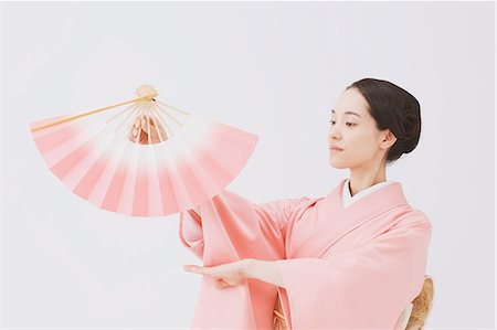 folding - Young Japanese woman in a traditional kimono against white background Stock Photo - Premium Royalty-Free, Code: 622-07743563