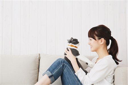 simsearch:6102-08481071,k - Japanese young woman in jeans and white shirt with cat on the sofa Stock Photo - Premium Royalty-Free, Code: 622-07743581