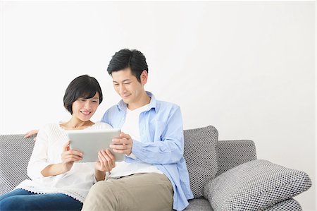 ethnic couples at home on sofa - Japanese couple on the sofa with tablet Stock Photo - Premium Royalty-Free, Code: 622-08122677