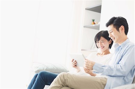 person searching online - Japanese couple on the sofa with tablet Stock Photo - Premium Royalty-Free, Code: 622-08123227