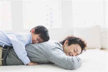 dad hugging son - Young boy laying on his fathers back Stock Photo - Premium Royalty-Free, Code: 622-08139004