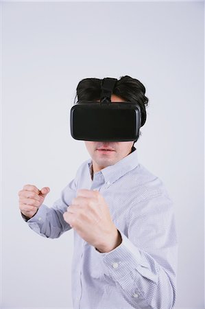 Japanese man using virtual reality device Stock Photo - Premium Royalty-Free, Code: 622-08519695